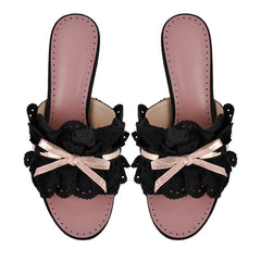 Pair of black eyelet lace slide mules with pink insoles and bows