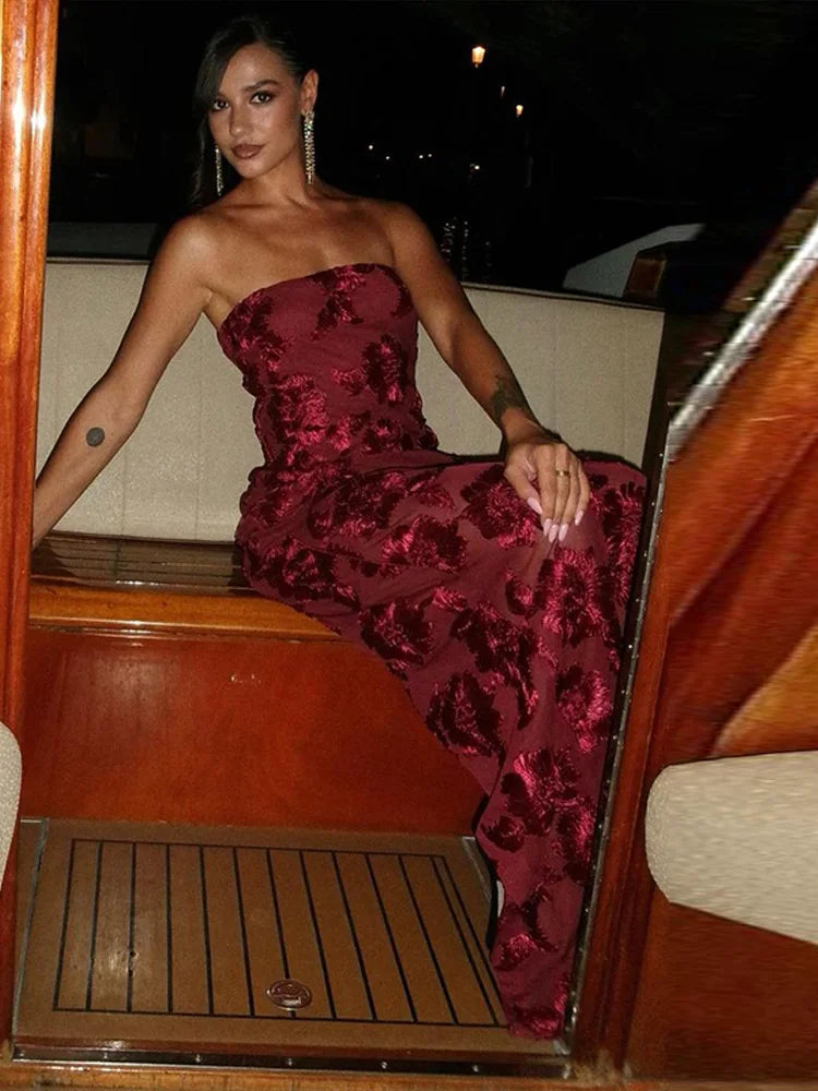 Woman in a strapless red dress on a boat at night