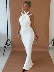 Woman in a white dress standing against a brown backdrop