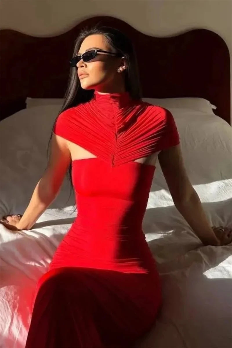 Woman in a red dress sitting on a bed with a neutral background