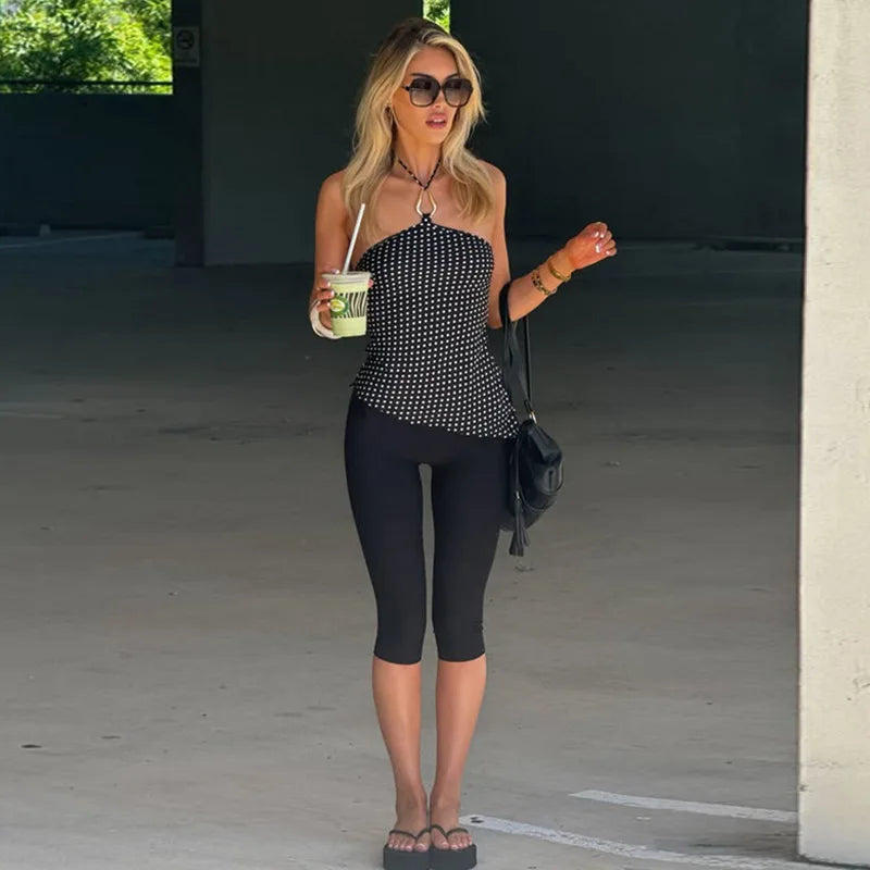 Full body view of a woman in a black polka dot halter neck crop top