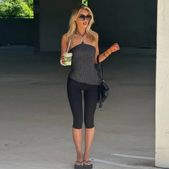 Full body view of a woman in a black polka dot halter neck crop top