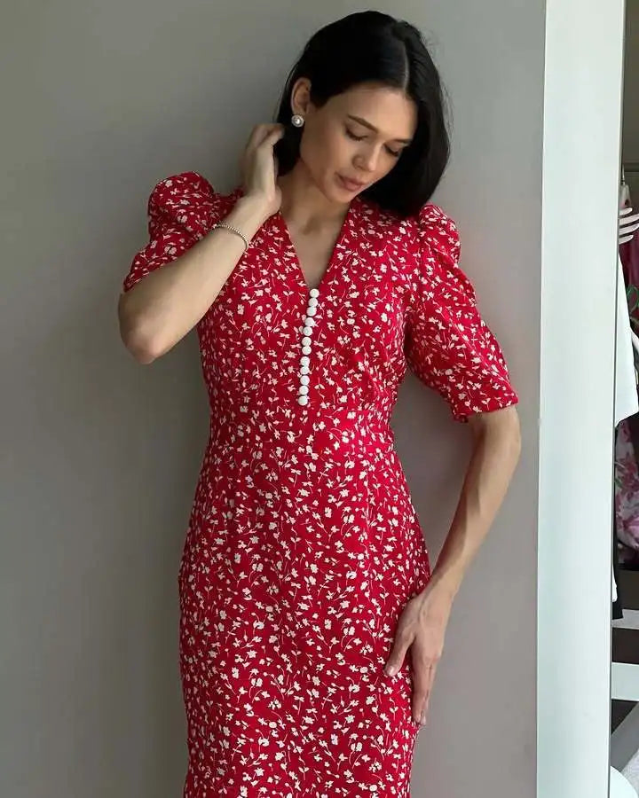 Woman wearing a red floral dress against a neutral background