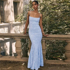 Woman in a light blue dress standing on a stone staircase with greenery in the background