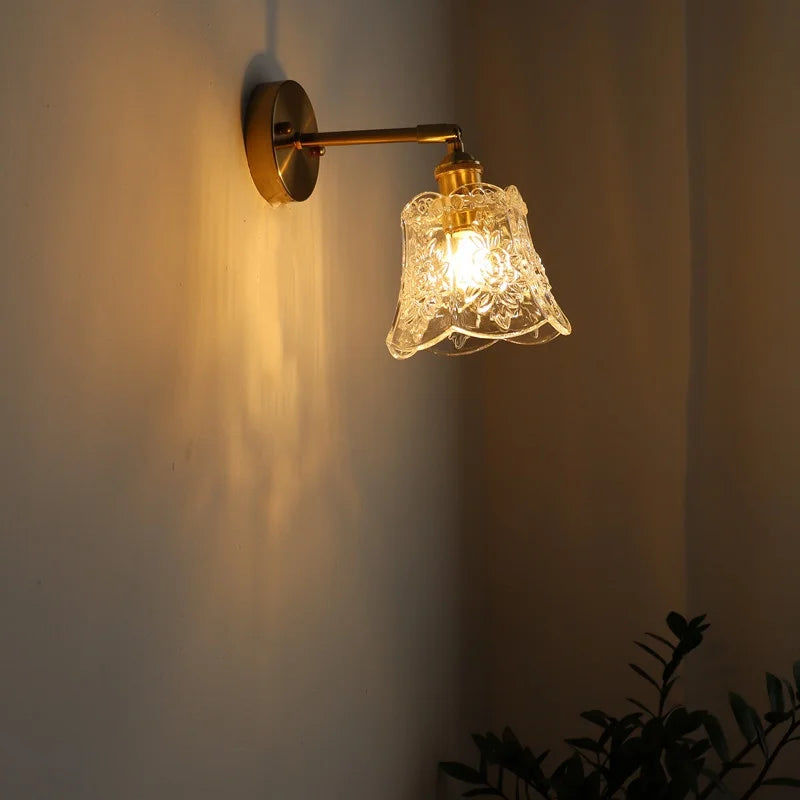 Wall-mounted light fixture with decorative glass shade on a plain wall.