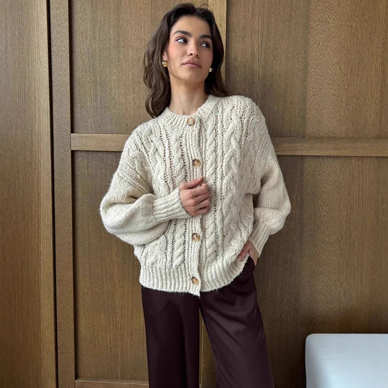 Woman wearing a cream knitted cardigan against a wooden panel background