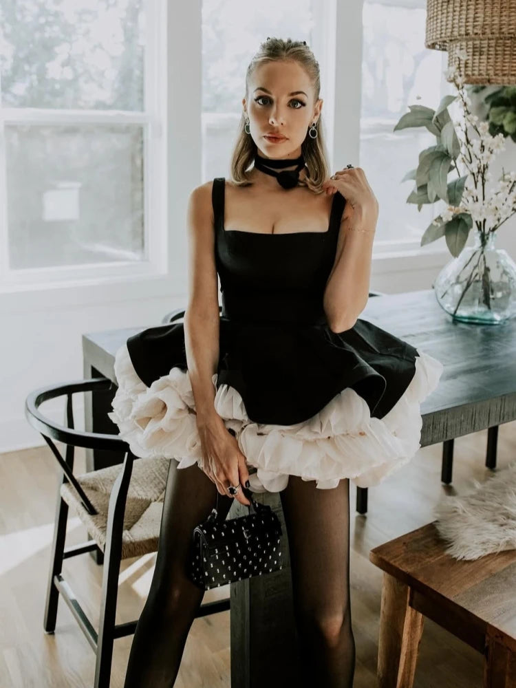 A woman in a black and white ruffled dress is sitting in a modern interior setting.