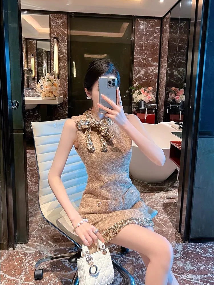 Woman taking a mirror selfie in a stylish dress and holding a handbag in a luxurious interior setting.
