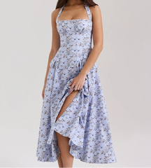 Woman wearing a floral dress with a slit on a plain background