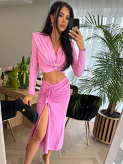 Woman in a pink outfit taking a mirror selfie in a modern interior setting.