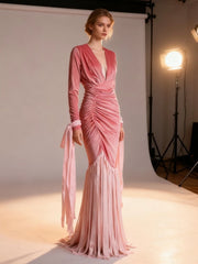 Model wearing a pink evening gown in a studio setting with lighting equipment.