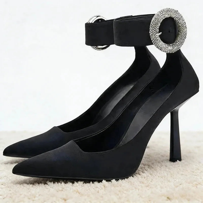 Black pointed toe pumps with rhinestone ankle strap buckle.
