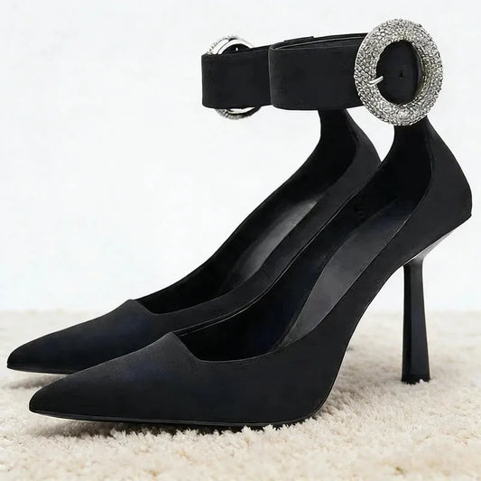 Black pointed toe pumps with rhinestone ankle strap buckle.