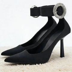 Black pointed toe pumps with rhinestone ankle strap buckle.