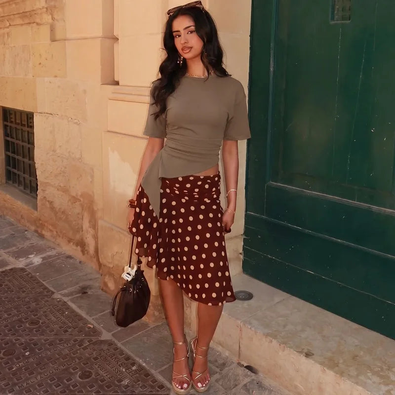 Model wearing a ruched asymmetrical hem crop top with a polka dot skirt