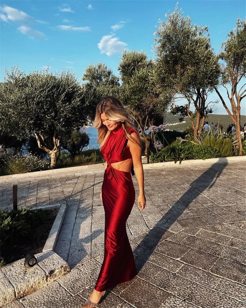 Woman in a red outfit standing outdoors with trees and water in the background