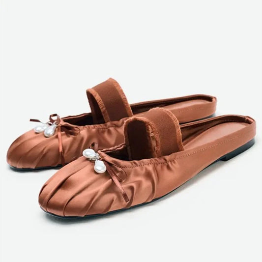 Pleated satin slide flats with pearl embellishments and elastic strap.