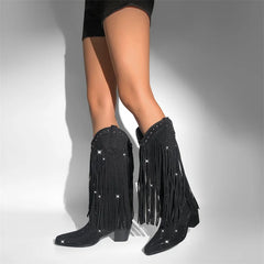 Black fringe boots with rhinestones worn by a person on a gray background