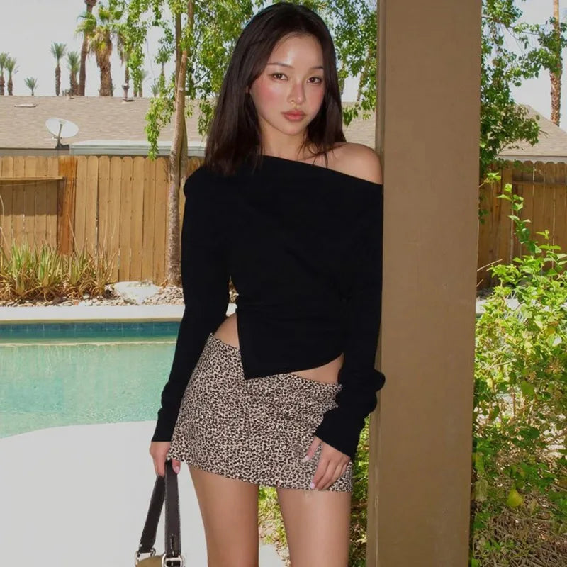 Woman in black off-shoulder top and leopard print shorts standing by a poolside.