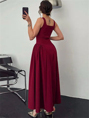 Woman in a burgundy dress taking a mirror selfie in a minimalistic room.