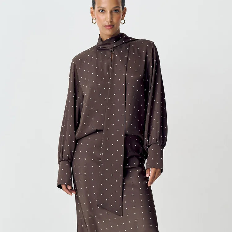 Woman wearing a brown polka dot blouse and skirt on a white background