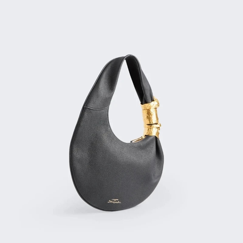 Black grained leather half moon shoulder bag with sculpted gold face hardware detail, side view