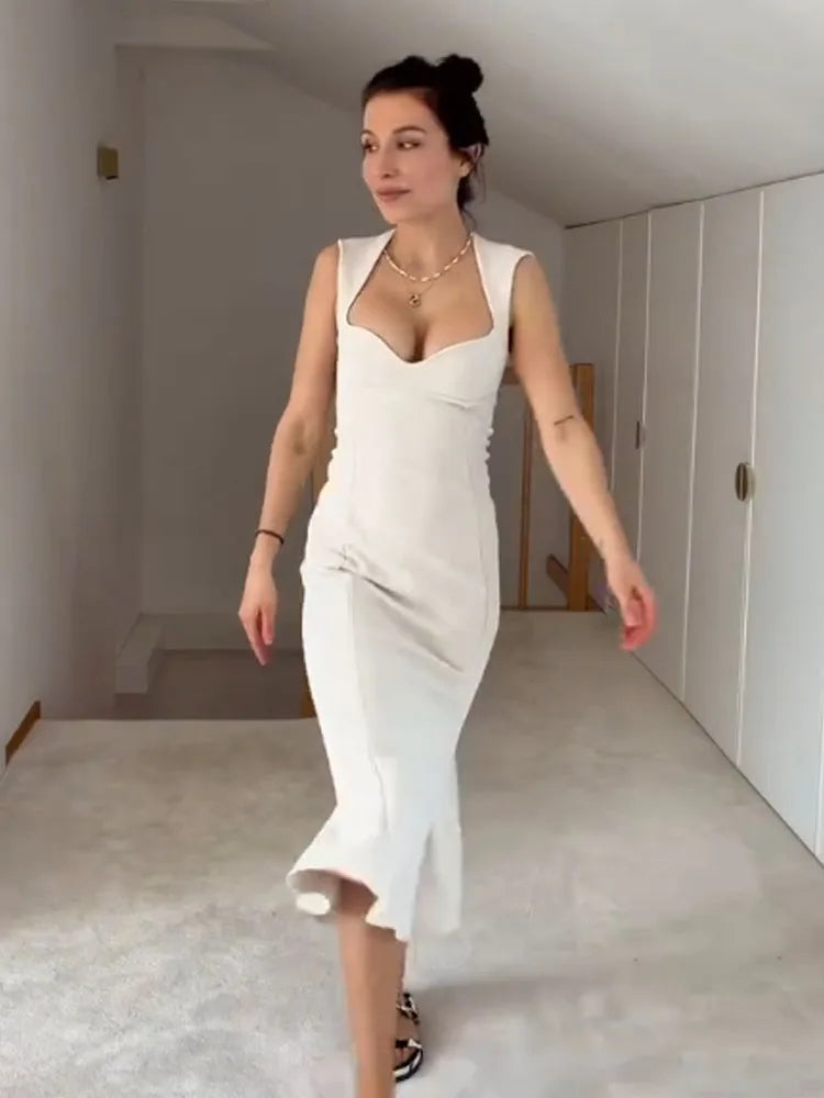 Woman in a white dress standing in a minimalistic room.