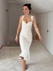 Woman in a white dress standing in a minimalistic room.