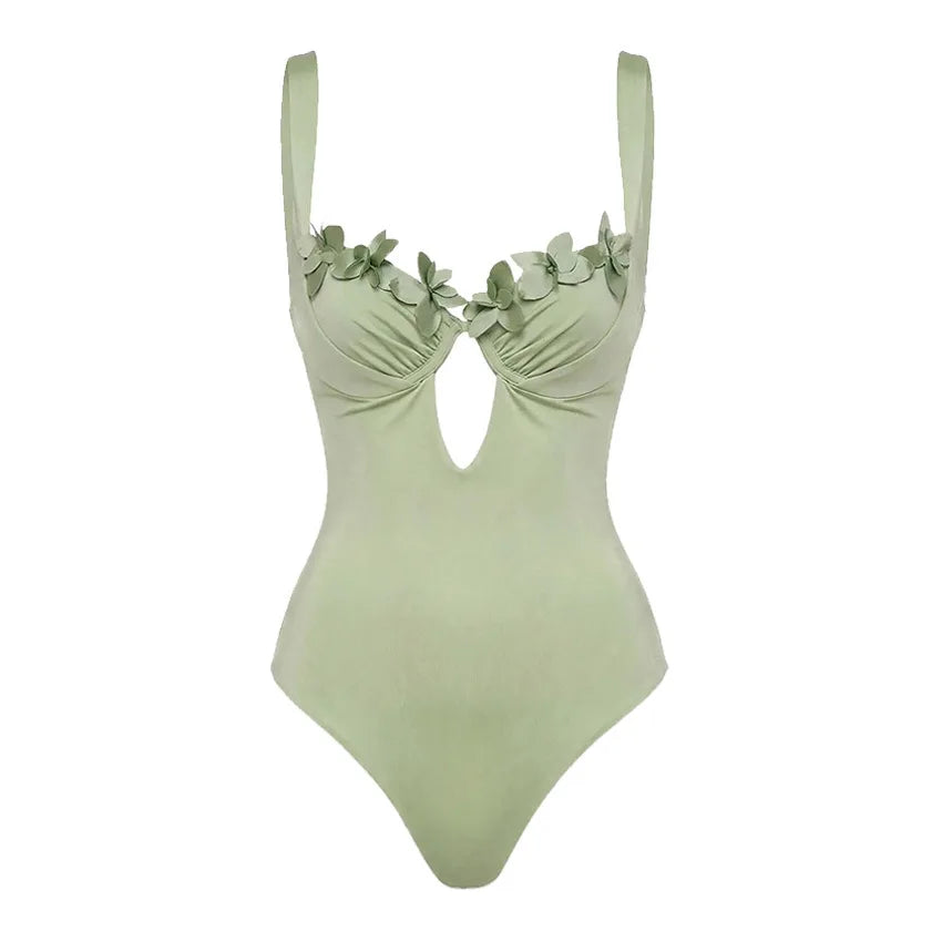 Close-up flat lay of a sage green one-piece swimsuit with floral embellishments.