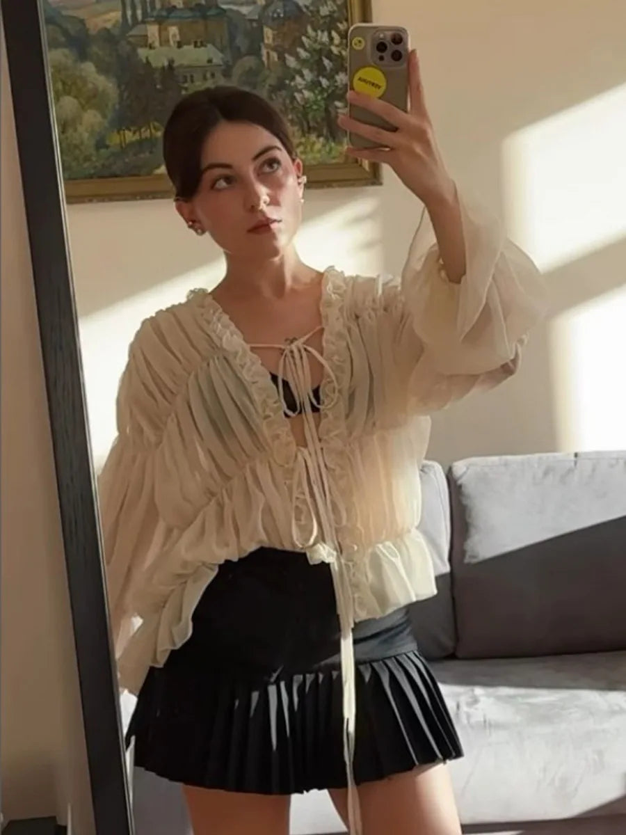 Woman taking a mirror selfie wearing a white blouse and black skirt in a living room.
