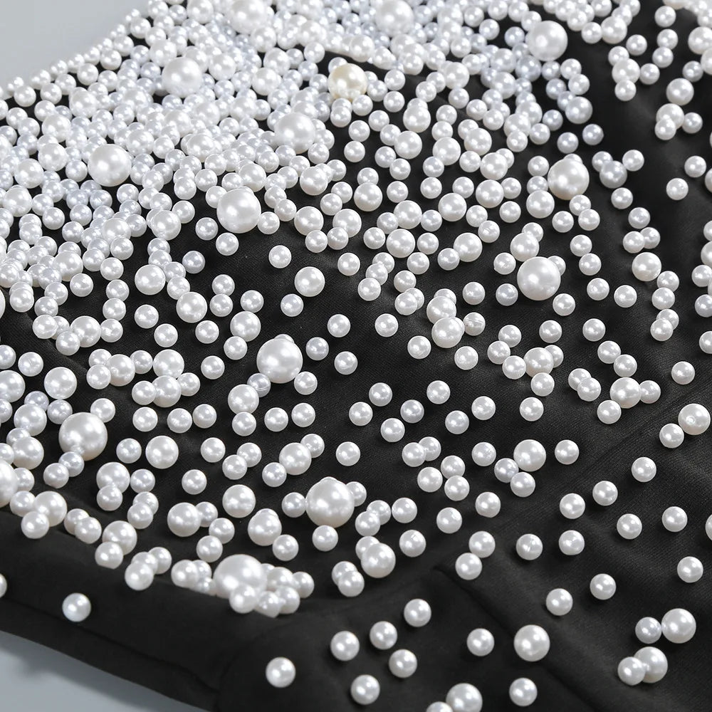 White pearls scattered on a black fabric background