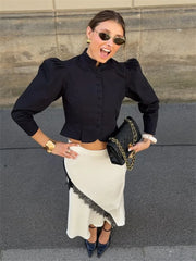 Woman in black top and white skirt posing outdoors