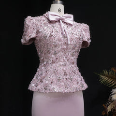 Pink sequin top with a bow on a mannequin against a black background