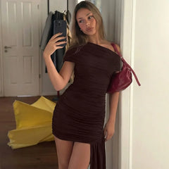 Woman taking a mirror selfie wearing a brown dress and red purse in a room.