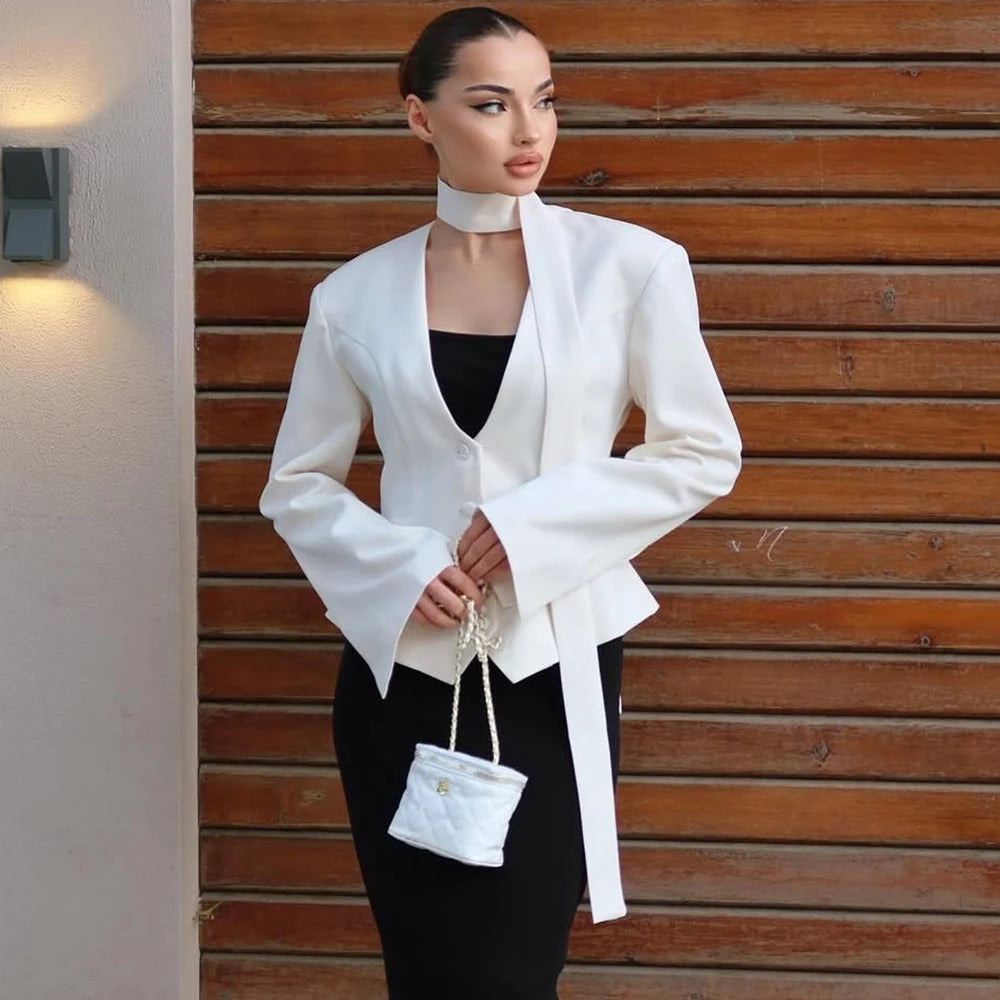 White slim v-neck blazer for women with single button closure and full sleeves against a wood wall