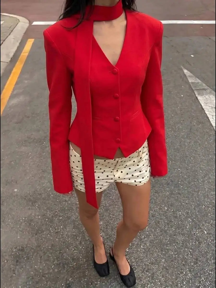 Model wearing a red padded shoulder v-neck blazer with white polka dot shorts.