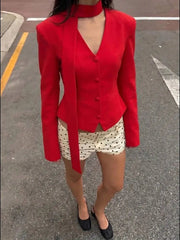 Model wearing a red padded shoulder v-neck blazer with white polka dot shorts.