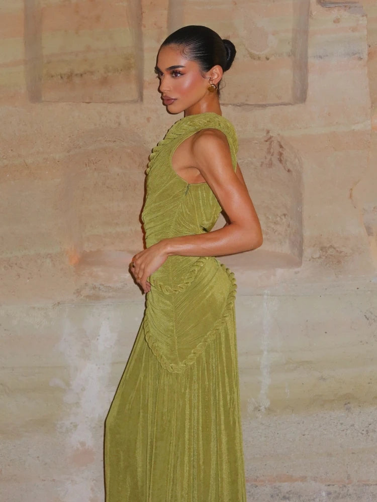 Woman in a green dress standing against a stone wall.