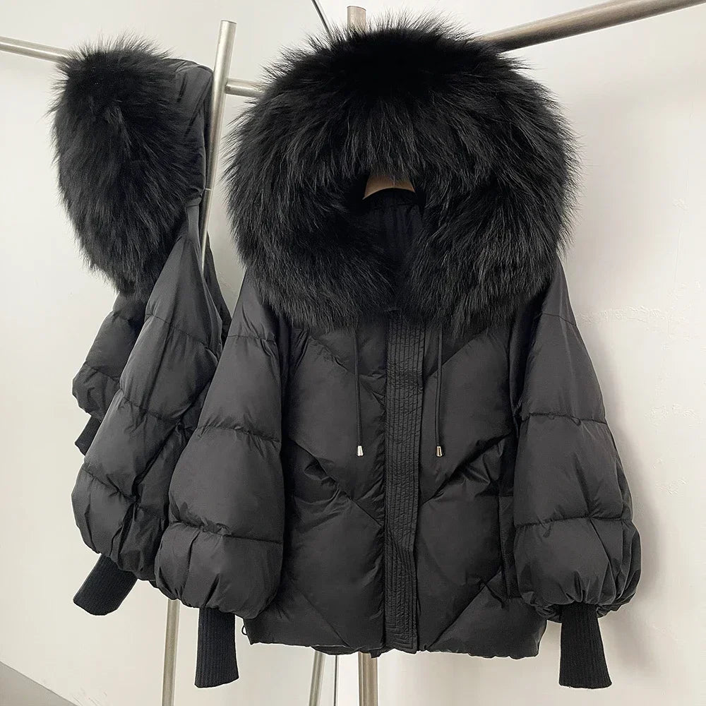Black puffer jacket with large fur hood on a rack against a white background