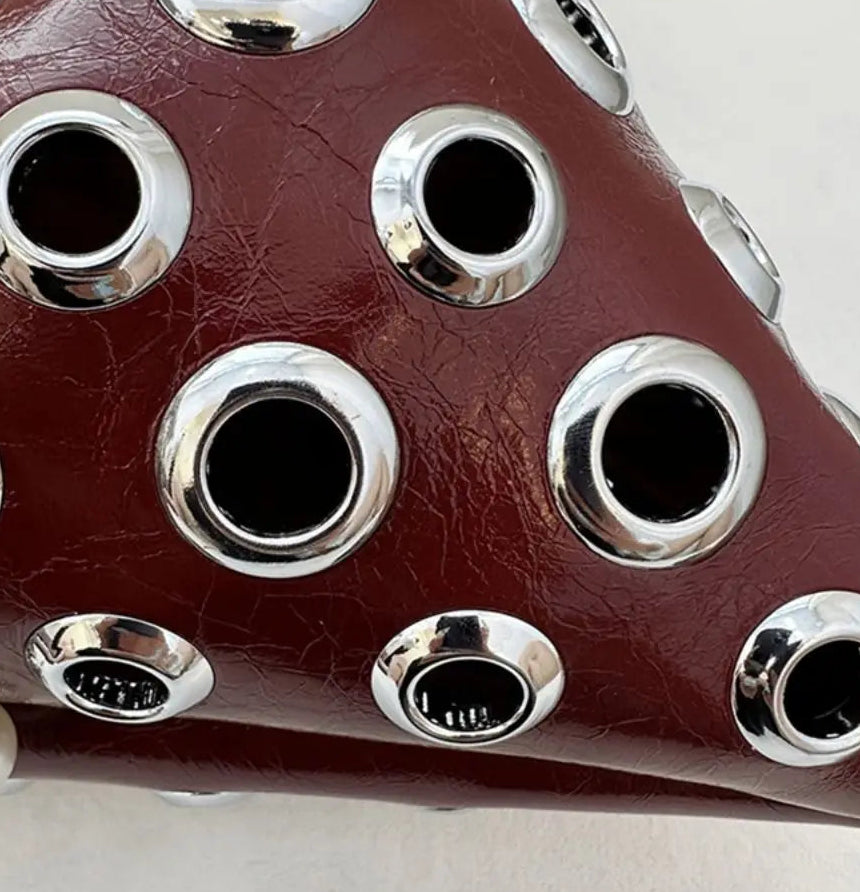 Close-up of a leather product with silver circular accents on a white background