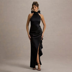 Woman wearing a black evening gown with a high slit on a beige background