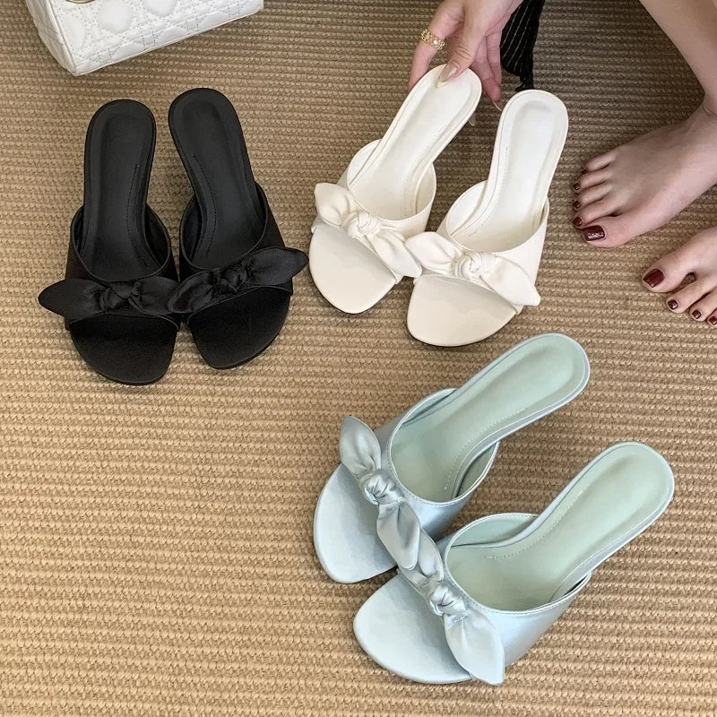 Assorted colored bow slide heels on a rug
