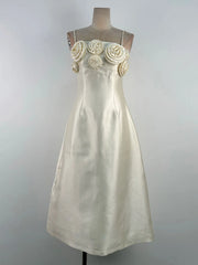 White dress with floral embellishments on a mannequin against a gray background