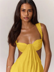 Woman wearing a yellow jumpsuit with cut-out design on a plain background