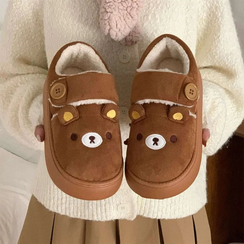 Person holding brown cartoon bear house slippers.