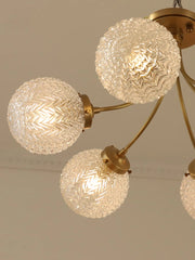 A modern glass ball ceiling light fixture hanging in a stylish living room. Golden Atelier 4