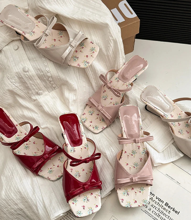 Pair of red and pink sandals with floral patterns on a surface.