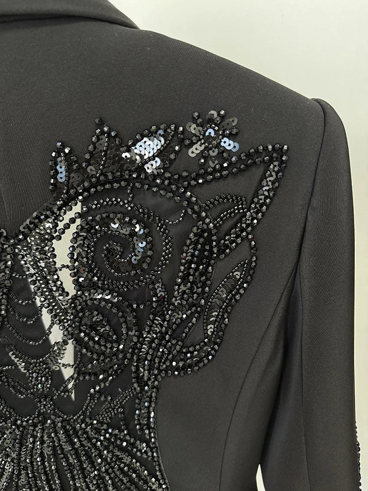 Black coat with intricate silver sequin embroidery on a plain background