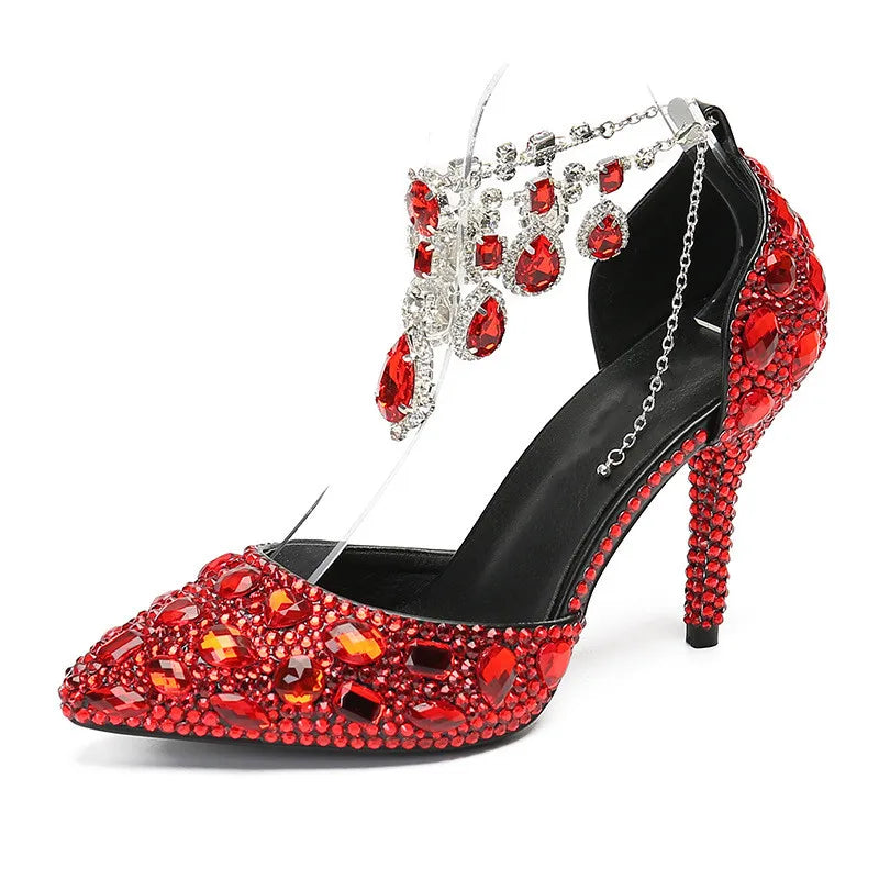 Black high-heeled shoe with red gemstones and silver chains on a white background
