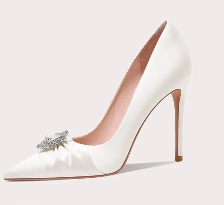 White high-heeled shoe with a decorative bow and gemstone on a light gray background